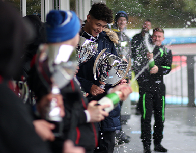 buckmore park celebrations champange spray with trophies